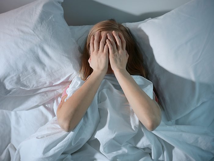 Weight gain, woman lies in bed with hands on her face