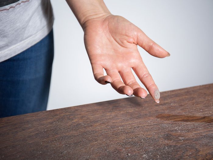 Allergies, woman running finger over dusty table