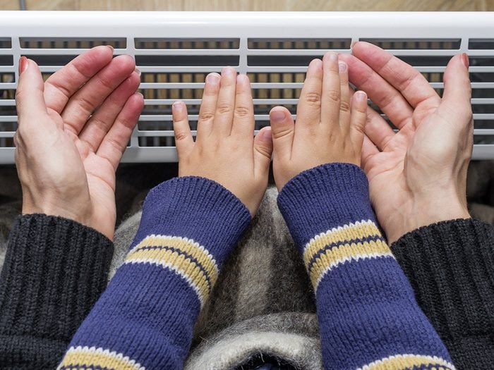 Eczema, mother and son holding their hands in front of a heater