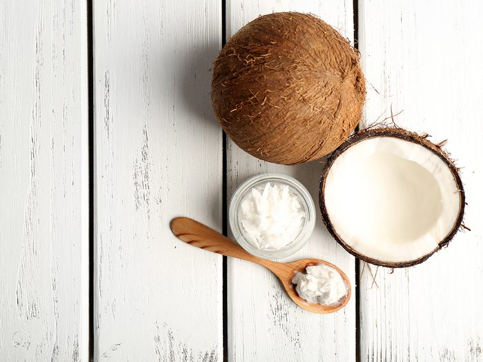 Healthy foods, a tub and spoonful of coconut oil next to a halved coconut