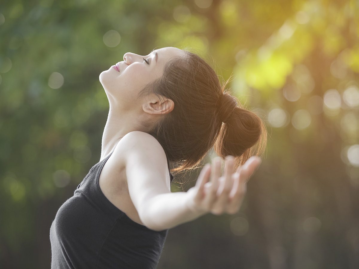 Shortness of breath, Woman breathes deeply and throws her arms wide outdoors