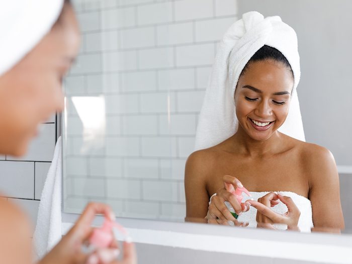Woman in bath towel applying skin cream