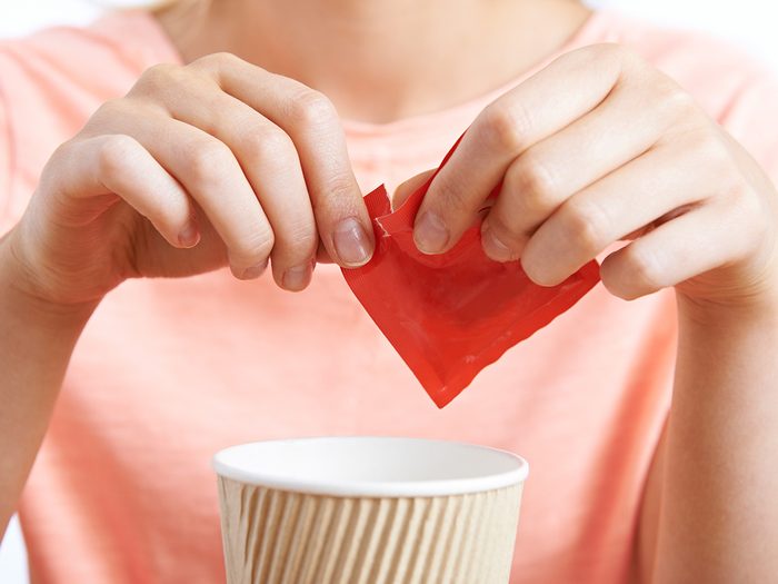Zero calorie foods, woman adding pack of splenda to her coffee