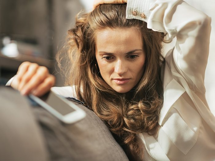 Woman with anxiety is very stressed, holding her cell phone