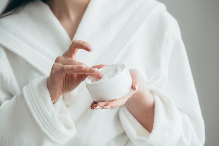 Beautiful groomed woman's hands holding a cream jar on the fluffy blanket. Moisturizing cream for clean and soft skin in winter time. Manicure beauty salon. Healthcare concept. Spa