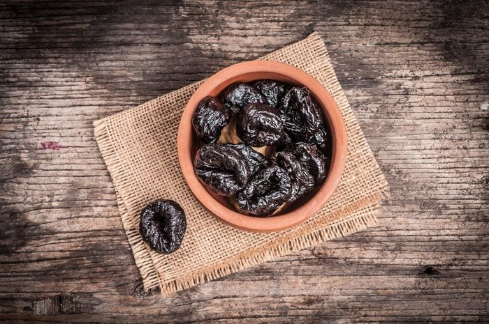 Prunes in bowl on linen and rustic wood
