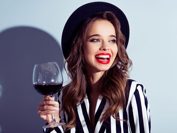 woman drinking wine with a smile and white teeth