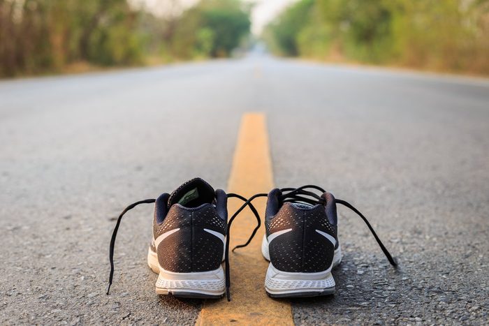 Close up new black running shoes on asphalt road in morning time