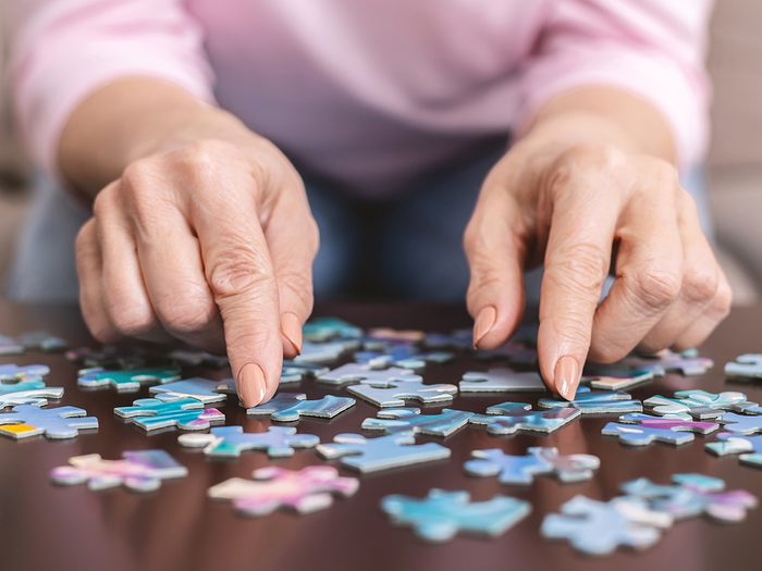 Senior,woman,hands,doing,jigsaw,puzzle,at,home,,panorama,,close