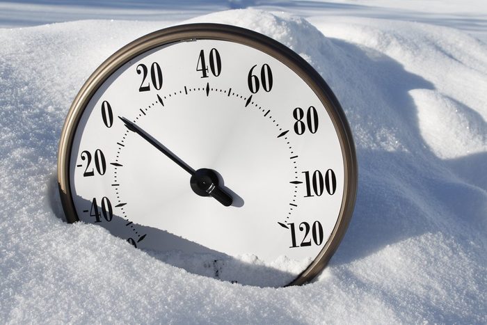 A temperature gauge in the snow reading around 0 fahrenheit.