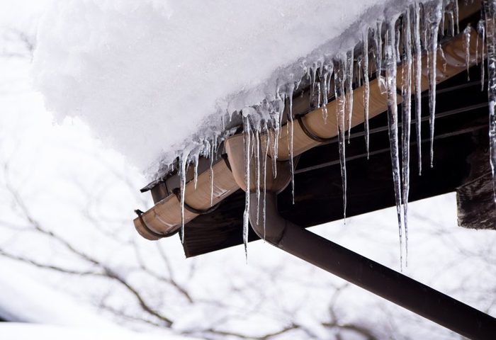 Sharp icicles and melted snow hanging from eaves of roof, Beautiful icicles slowly gliding of a roof.