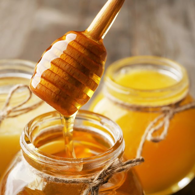 Pouring aromatic honey into jar, closeup