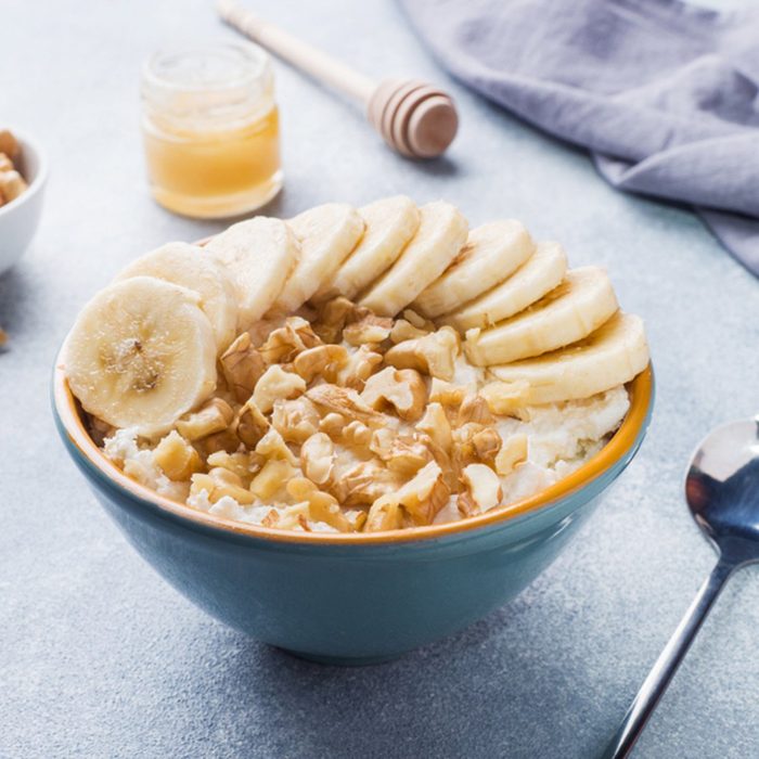 Healthy breakfast. Cottage cheese with banana and walnuts on grey background