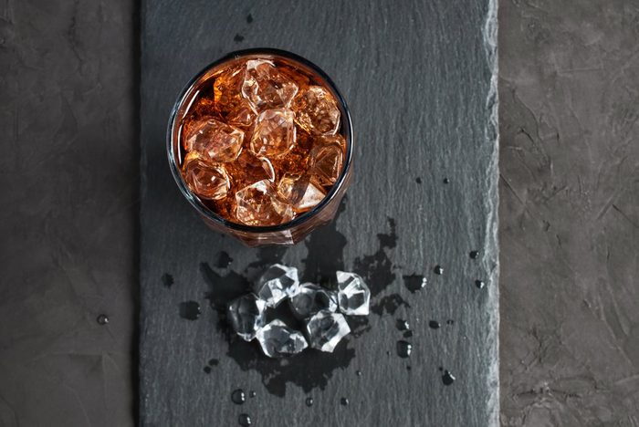 Cola with ice cube on black slate board