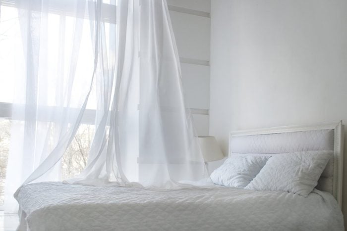 White themed bed sheets and white curtain in the morning, bedroom interior