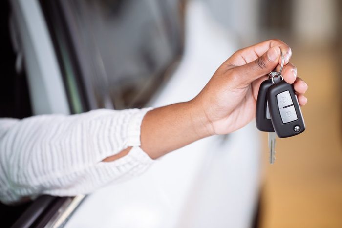 african american woman with her new car showing key