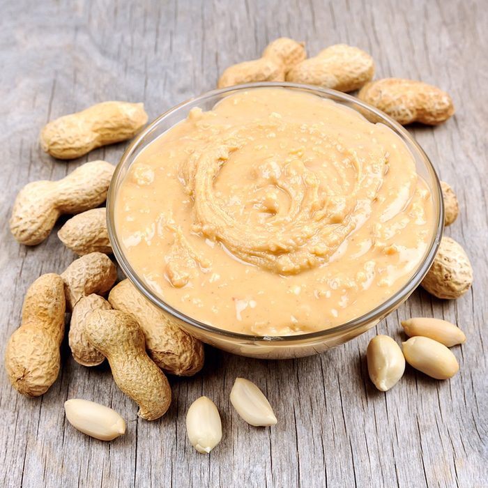 Creamy peanut butter with nuts on wooden texture