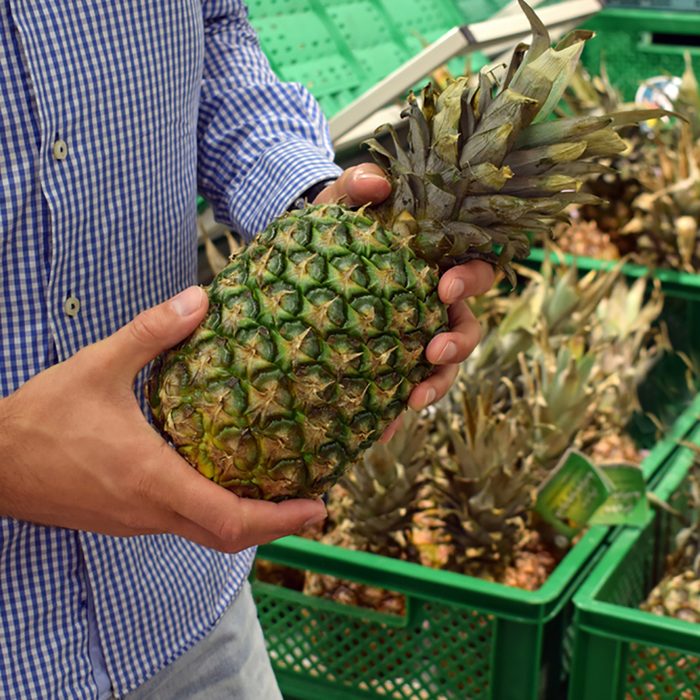 The guy chooses pineapples in the supermarket.