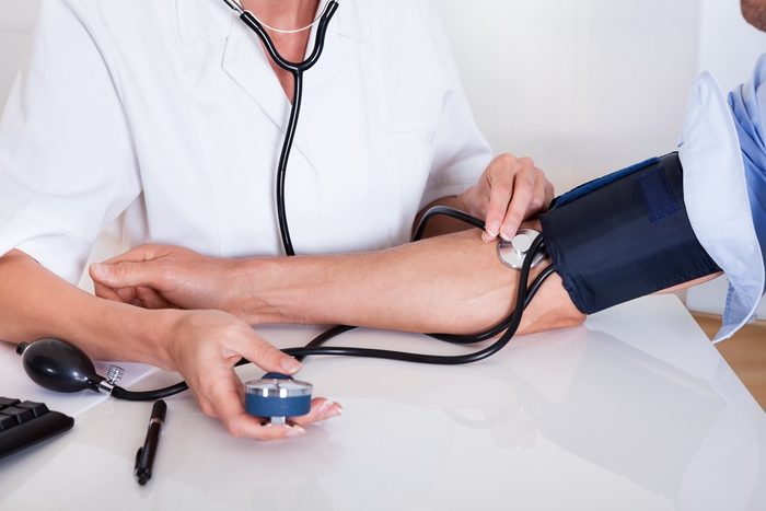 Attractive young female doctor or nurse taking a male patients blood pressure using a sphygmomanometer
