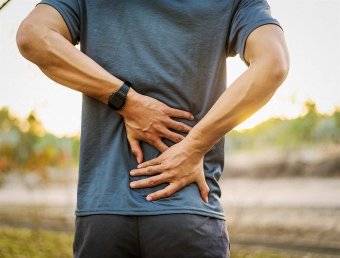 Back pain, close up young man has injury during outdoor exercise