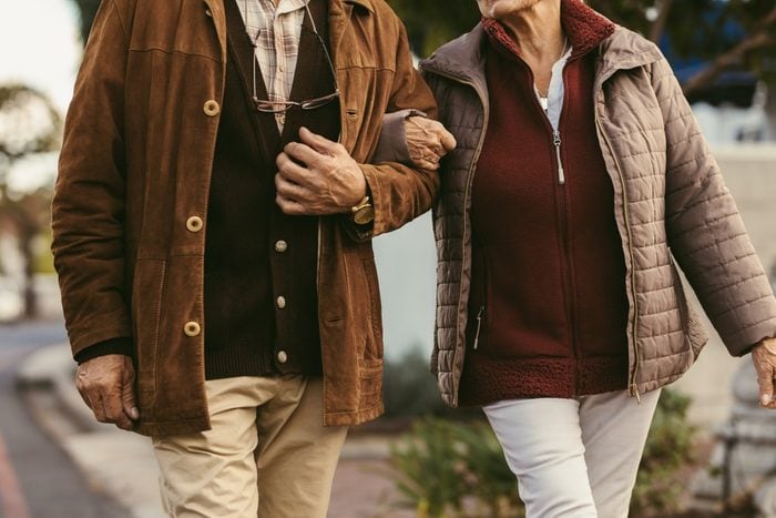 Close up of senior couple holding hands and walking together outdoors. Midsection of old couple walking hand in hand outdoors.