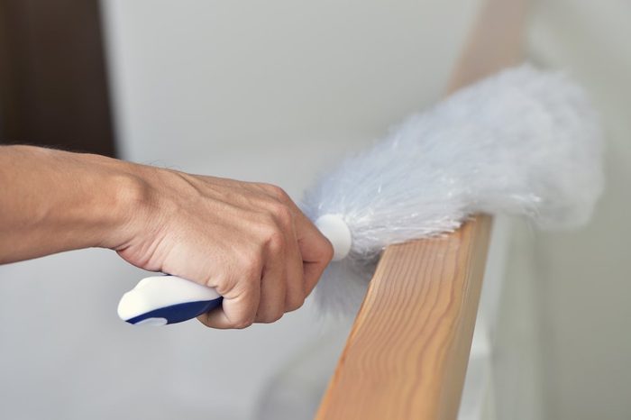 closeup of a young man dusting the house with a white microfiber duster