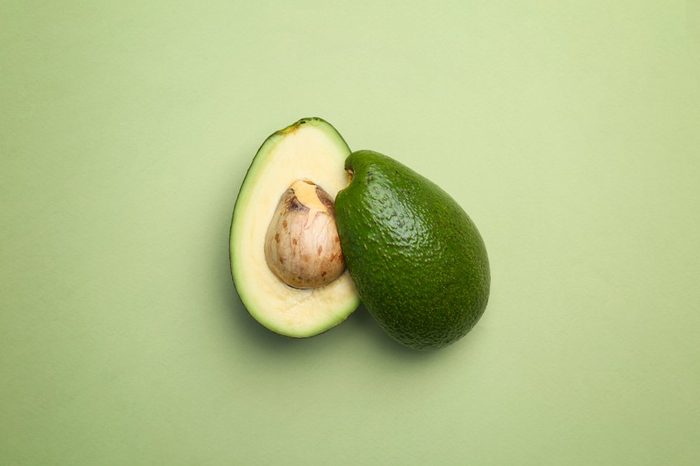 Cut avocado on color background, top view