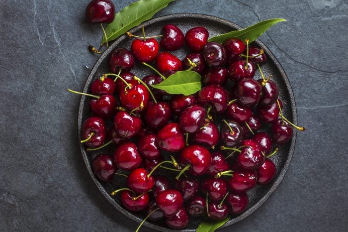 Fresh cherry on black plate on slate background. Top view
