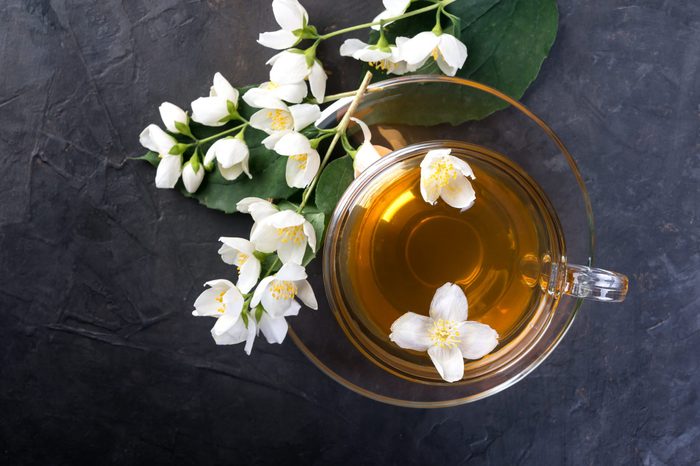 Jasmine tea with jasmine flowers on a dark background, top view