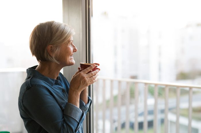 Senior woman at the window holding a cup of coffee