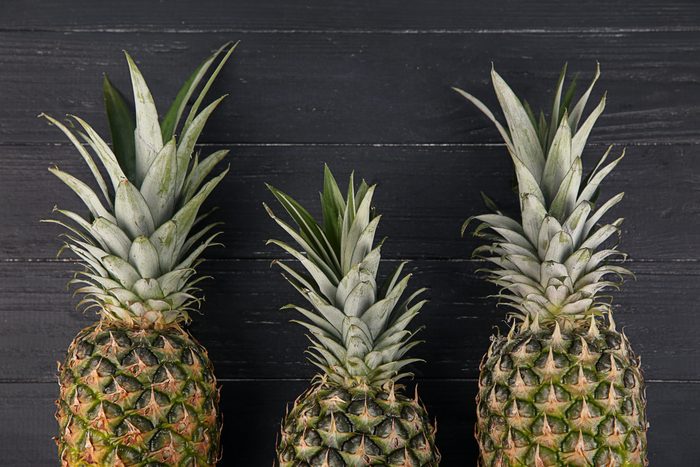 Fresh pineapples on dark wooden background