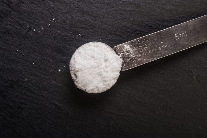 powdered sugar in a metal spoon on a gray background