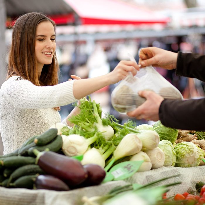 Millennial young woman buying fresh vegetables at farmer's market