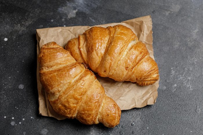 French croissant. Freshly baked croissants with jam on dark stone background. Tasty croissants with copy space