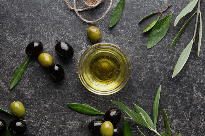 Glass bowl with olive oil on dark background