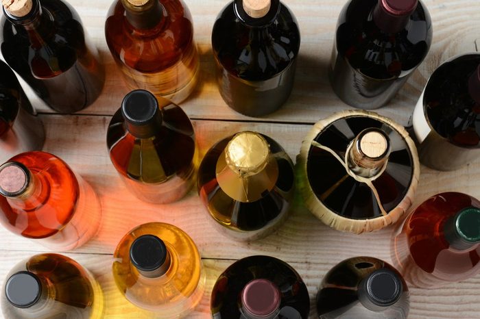 High angle shot of assorted wine and champagne bottles on a rustic wood table. Horizontal format.
