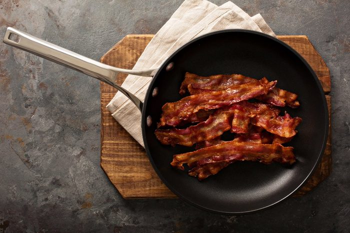 Cooked sizzling hot tasty crispy bacon on a skillet ready for breakfast overhead shot