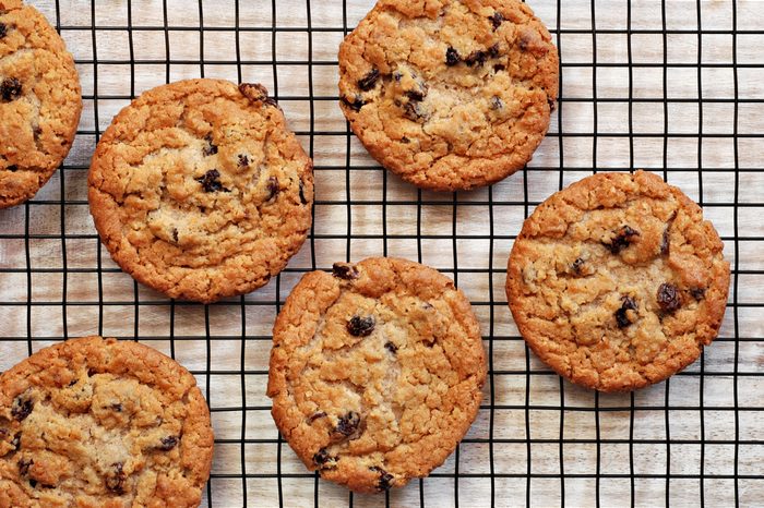 Freshly baked oatmeal raisin cookies on cooling rack over rustic wood background. Closeup from above with natural directional lighting. 