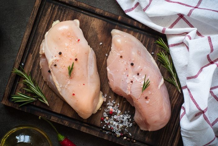 Raw chicken fillet on cutting board with sea salt pepper rosemary. Food background, cooking ingredients. Fresh meat.