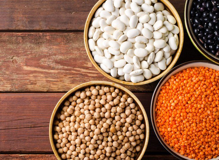 Assorted beans in bowls with red lentil, chick-pea and kidney bean on wooden background. Horizontal top view, copy space