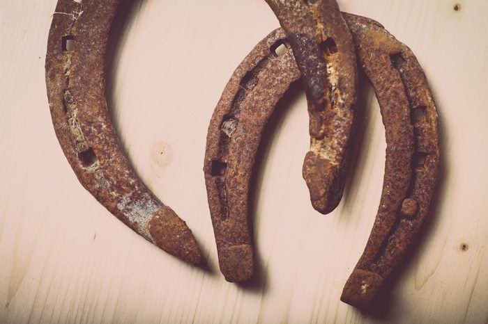 Color shot of two horse shoes on a wooden background.