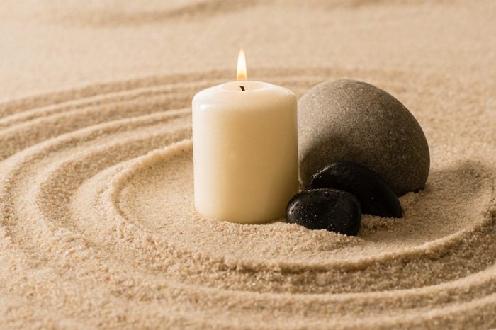 Spa atmosphere candle with zen stones in sand still nature