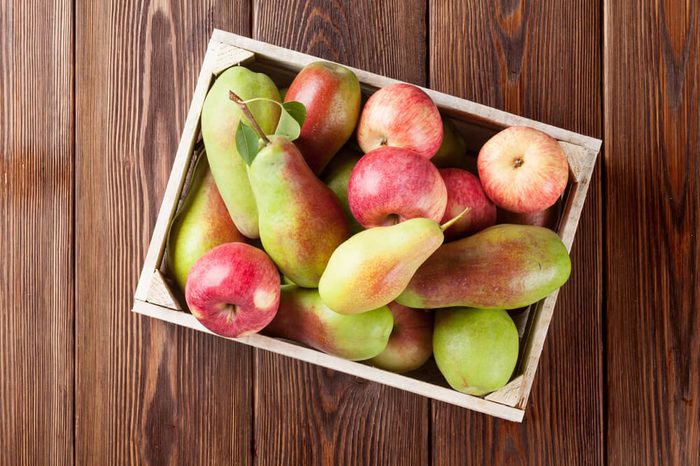 Pears and apples in wooden box on table. Top view