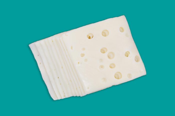 Top view of several slices of low sodium Swiss cheese on a wood cheese board.