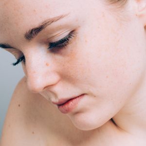 Young beautiful freckles woman face portrait with healthy skin