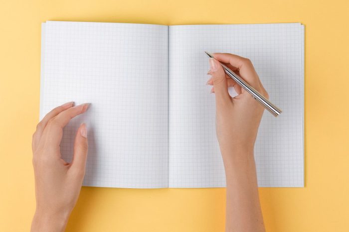 girl writes in an open notebook top view on yellow background, office desk in the flat lay. women write in a notebook
