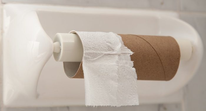 Empty roll of toilet paper mounted on a tiled wall