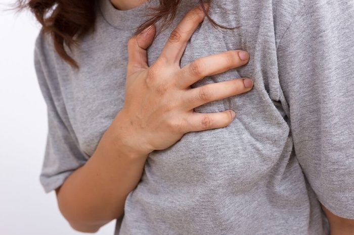 Severe heartache, woman suffering from chest pain, having heart attack or painful cramps, pressing on chest with painful expression.