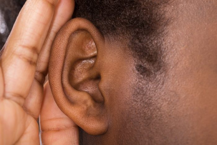 Close-up Of An African Woman Trying To Hear With Hand Over Ear