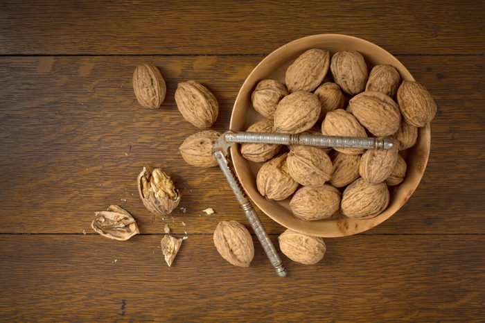 Above View of Walnuts grown in Oregon, in a Wooden Bowl on a Dark wood Table Background with some cracked and the nutcracker. It's horizontal with room or space for copy, text, crop or your words